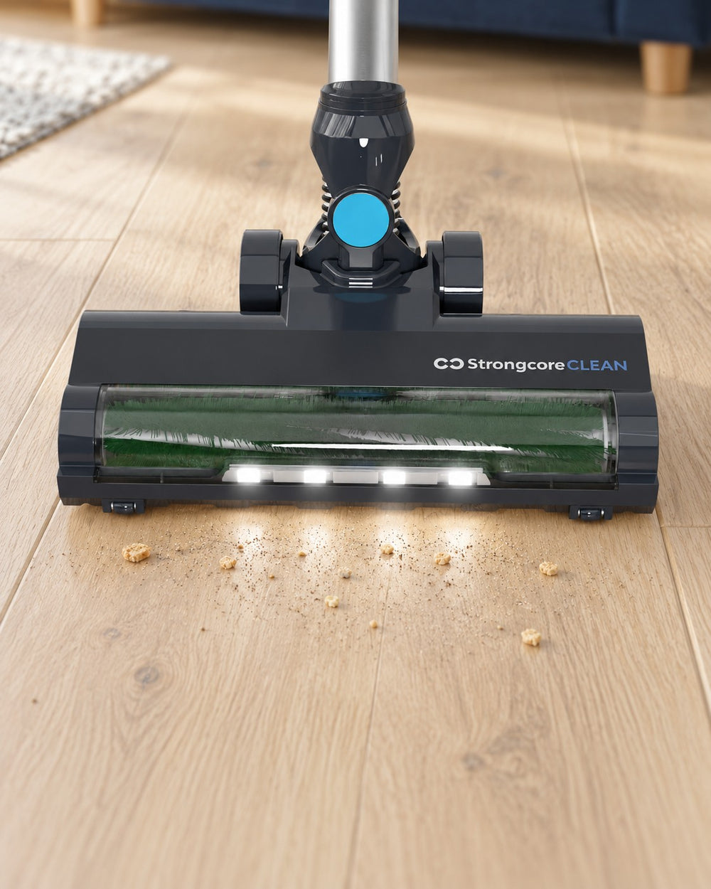 CLEAN's four-LED floor brush picking up dry crumbs from pale oak flooring.
