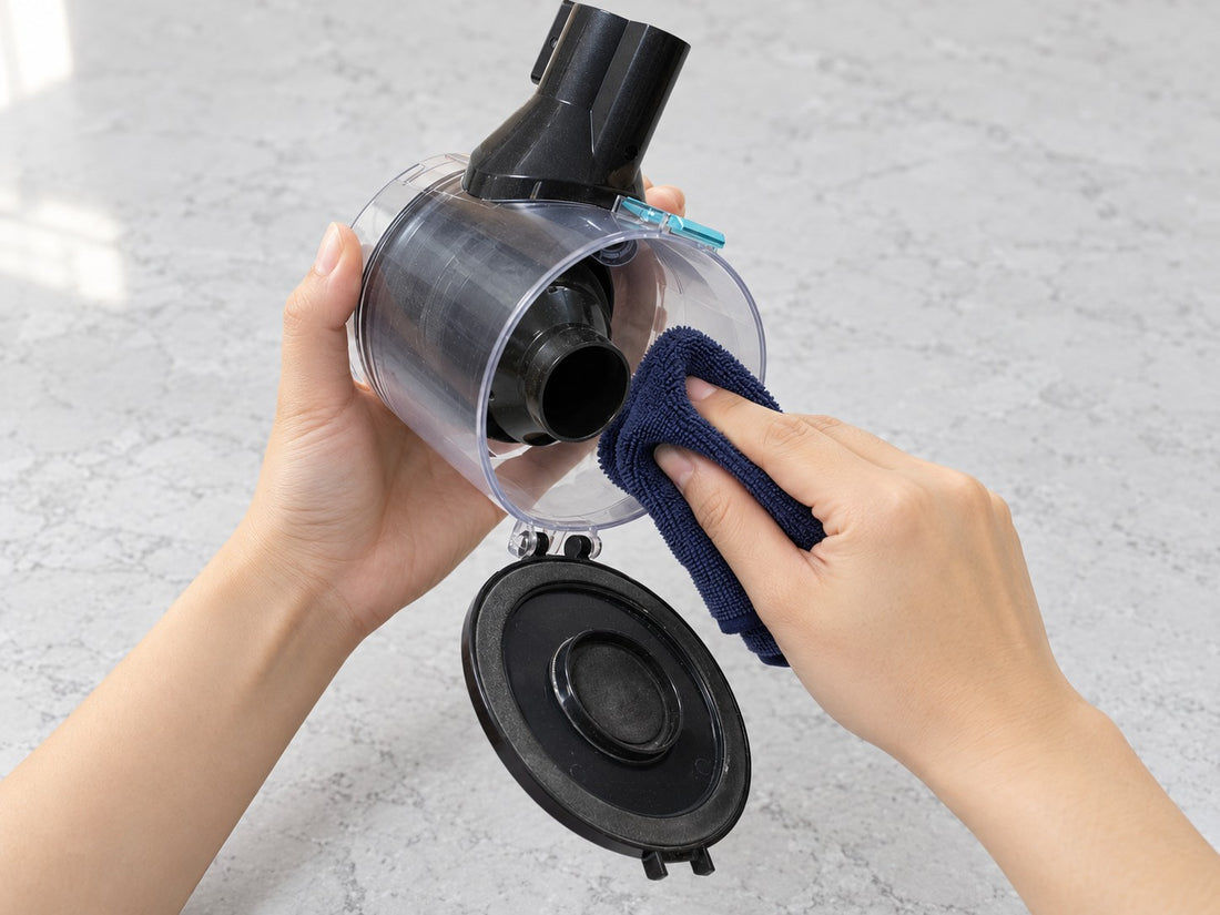 A hand wiping the inside wall of CLEAN's detached dust cup through its open base.
